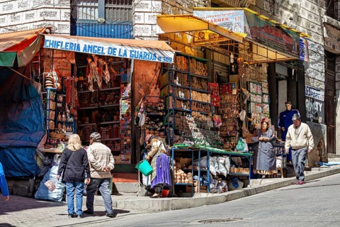 A busy market stall with souvenirs on a street corner surrounded by people, The witches' market of