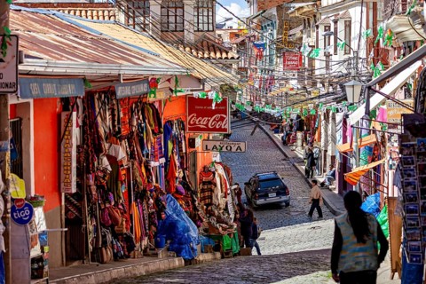 A lively street with colourful shops and people in a mountainous setting, the witches' market in La