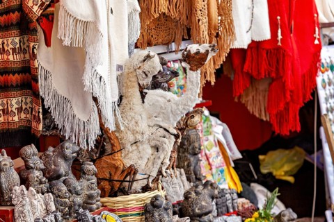 A market stall with a llama figure and colourful textiles represents Andean culture, The witches'