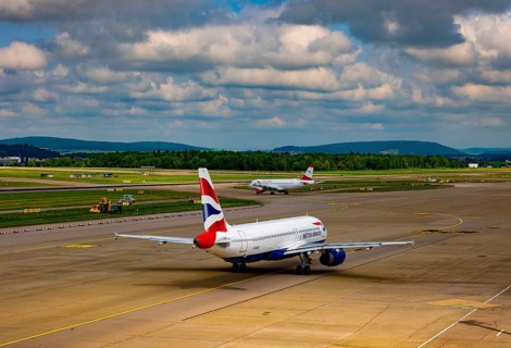 British Airways and Austrian Airlines Passenger Airplane Taxiing on Runway in a Sunny Summer Day