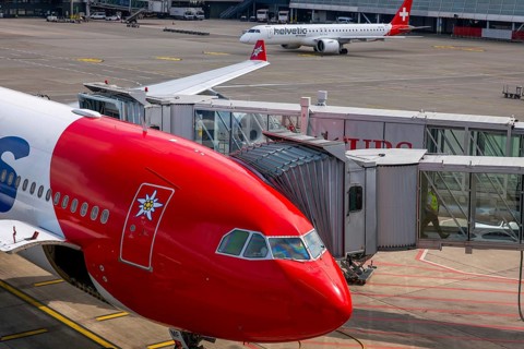 Zurich Airport and Passenger Airplane and Boarding Bridge Gate on Airfield in a Sunny Summer Day