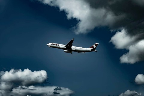 Swiss Airlines Passenger Airplane Flying Against Blue Sky and Clouds in a Sunny Summer Day From the