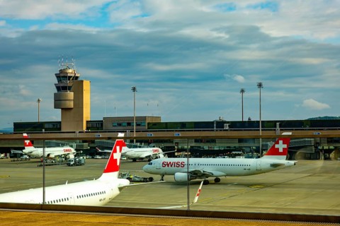 Swiss Airlines Passenger Airplane and Air Traffic Control Tower on the Airfield in a Sunny Summer