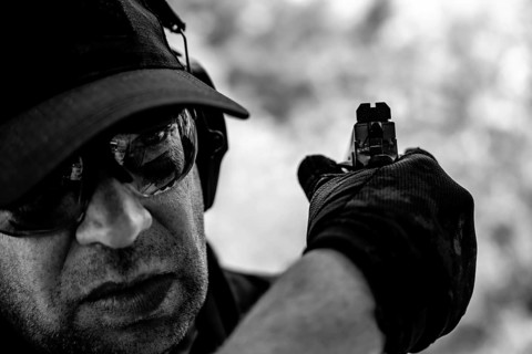 Man with Cap and Protection Eyeglasses Holding a Handgun Backward in Switzerland