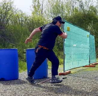 Man with Cap and Protection Eyeglasses Running and Holding a Handgun Backward in IPSC Shooting