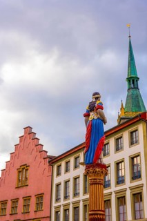 Old Town with House and Water Fountain with Statue and Tower with Sky and Clouds in a Sunny Autumn
