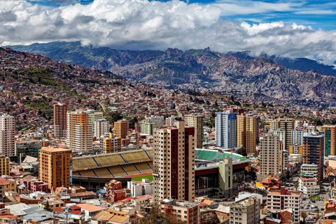 Urban landscape of La Paz with skyscrapers, a stadium and mountains in the background, The houses