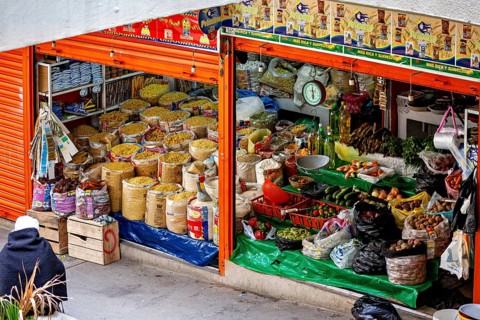 Lush market stall with different types of grain and traditional foods, small shops and restaurants