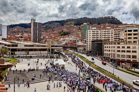 Bustling city atmosphere with people gathering in a large square surrounded by urban architecture
