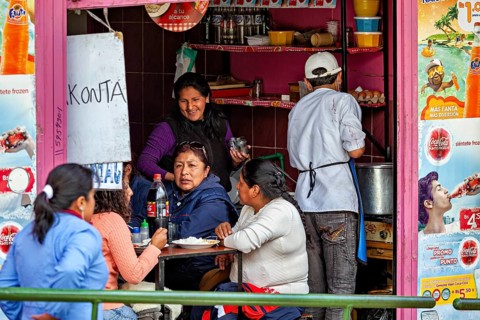 People enjoy their meals in the middle of a lively street snack bar, surrounded by colourful