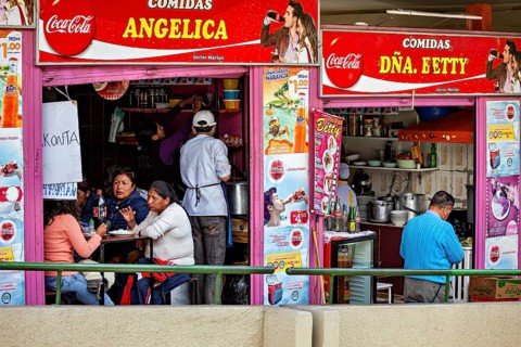A busy street snack bar with people sitting at tables and eating, surrounded by colourful