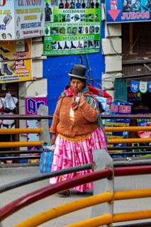 A woman in traditional dress walks through a colourful market street in Bolivia, A traditional