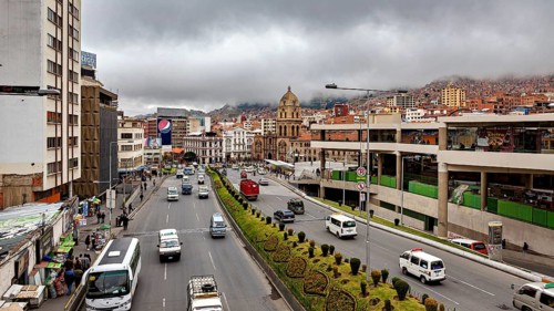 Urban scene with a wide street, traffic, a church and clouds over the mountains, The main streets
