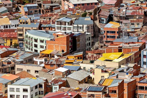 Densely packed urban cluster of houses with colourful roofs, The houses and skyscrapers of downtown