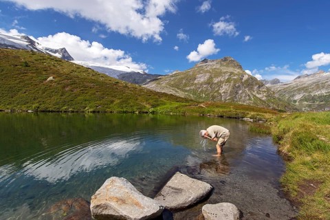 Hiker refreshes himself in the Salzbodensee lake on the glacier show trail in the Tauerntal valley,