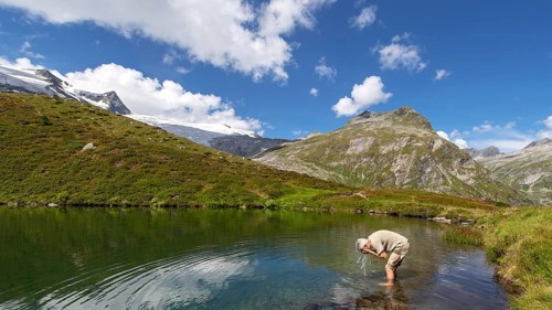 Hiker refreshes himself in the Salzbodensee lake on the glacier show trail in the Tauerntal valley,