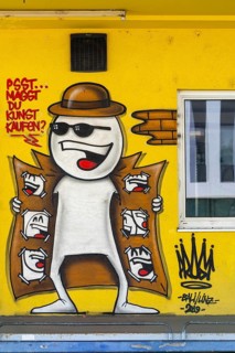 Funny comic-style graffiti with a figure in a trench coat on a yellow wall, at the harbour in Linz,