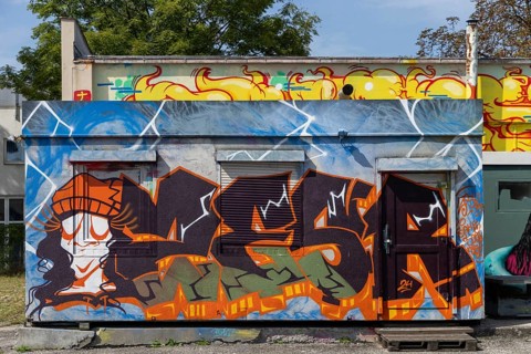 Colourful graffiti wall with lively figures and letters in an urban environment, at the port of