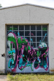 Garage door decorated with colourful graffiti and abstract shapes, at the port of Linz Upper