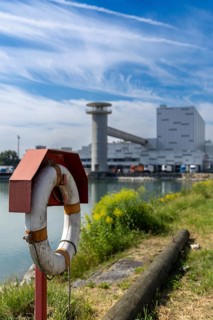 Lifebuoy in front of an industrial area in a partly cloudy sky, at the harbour of Linz Upper