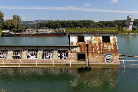 Rusty, dilapidated building on the water in a natural environment, at the harbour Linz Upper