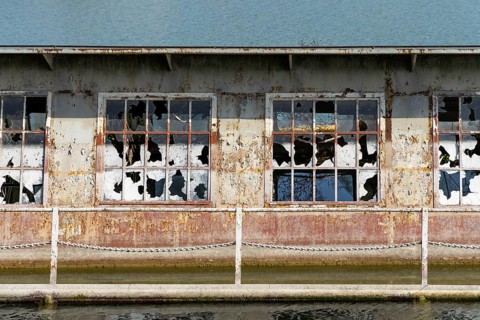 Close-up of broken windows of a rusty building on the waterfront, at the harbour of Linz Upper