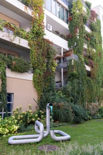 Modern façade with lush greenery and a sculpture in the front garden, Linz city centre Upper