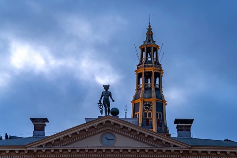 Statue of the god Mercury on the roof of the Korenbeurs former grain exchange and the steeple of