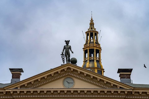 Statue of the god Mercury on the roof of the Korenbeurs former grain exchange and the steeple of