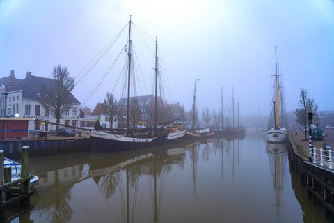 Typical canal with sailing boats in the winter fog, Harlingen, Friesland, Netherlands