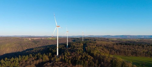 Wind turbines on a wooded hill under a clear blue sky, near Schorndorf im Remstal,