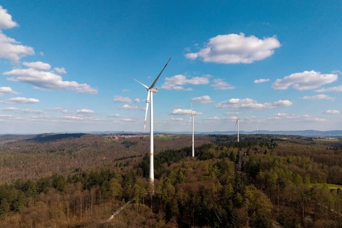 Green landscape with wind turbines and slightly cloudy sky, maintenance work, repair, near