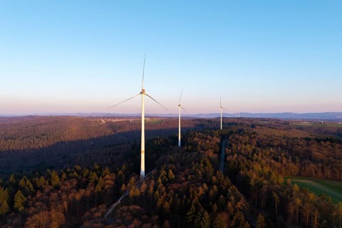 A wind farm spreads out over a wooded area under a clear sky, near Schorndorf in the Rems Valley,