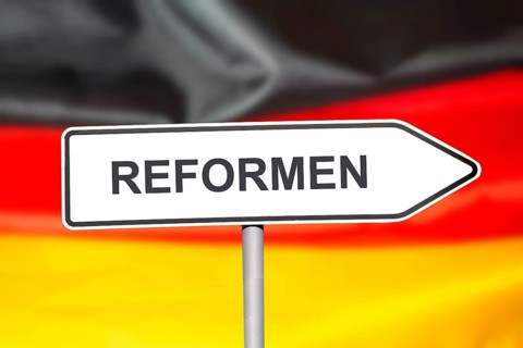(Photomontage) Directional arrow with the inscription REFORMEN in front of a German flag