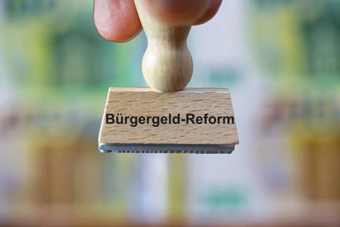 (Photomontage) Stamp with the inscription BÜRGERGELD in front of blurred euro banknotes in the