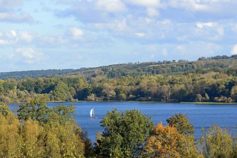 View of the Möhnesee with sailing boat, autumn atmosphere, blue cloudy sky, Möhnetalsperre, North