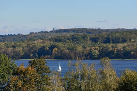 View of the Möhnesee with sailing boat and the Möhnesee tower, autumn atmosphere, blue sky,