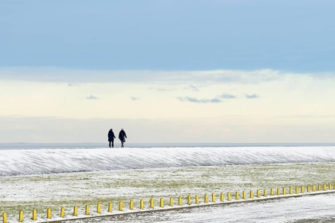 North Sea coast on a winter's day, people walking over a snow-covered dyke, Norddeich, Lower