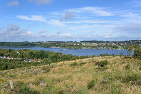 View over the Möhnesee, Körbecke village with the lake park and the lakeside promenade, blue cloudy