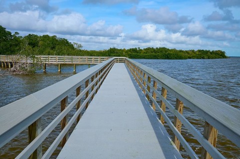 A long wooden walkway leads into the water, under a cloudy sky, West Lake View Point, Everglades