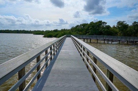 A boardwalk with railings stretches along a calm lake under a cloudy sky, West Lake View Point,