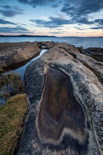 Rocky coastline with water puddles and grass during a sunset-lit evening, Skjeberg, Sarpsborg,