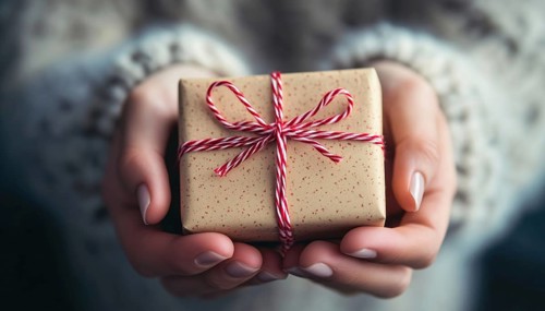 Close-Up Shot Of Hands Holding A Small Present Depicting A Gesture Of Giving And Receiving In A