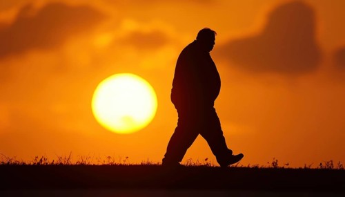 Sunlit Fat Man Silhouetted Walking Against The Sun'S Rays, Exuding A Sense Of Peace And Contentment