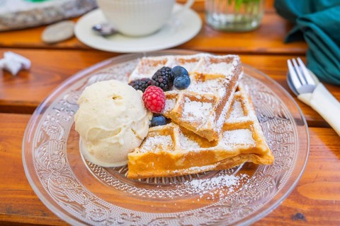 Close-up of waffles with berries and ice cream on a plate on a wooden table