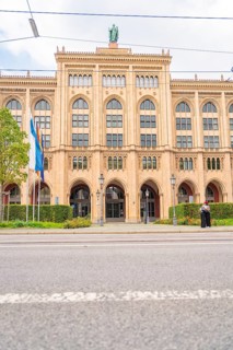 Front view of an imposing historic building with flags and green plants, Munich, Germany