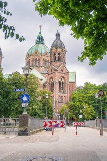 Impressive church with twin towers surrounded by trees on a cloudy day, Munich, Germany