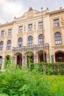 A magnificent historic building with ornate facades surrounded by lush green plants, Munich,