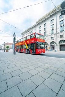 A red double-decker bus for city tours in front of historic buildings in Munich, Munich, Germany