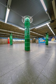 Spacious underground station with striking green columns in a simple atmosphere, Munich, Germany